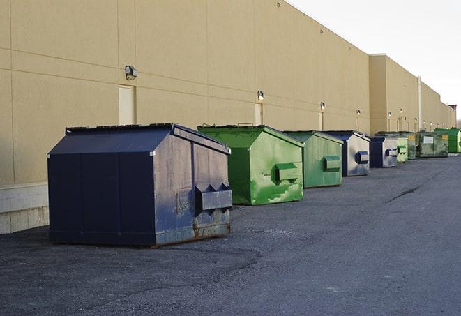 a series of colorful, utilitarian dumpsters deployed in a construction site in Alcester